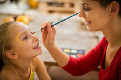 Face painter decorating a smiling young girl's face at a Houston birthday party.